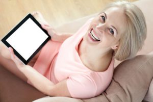 Woman sitting on couch holding an electronic tablet