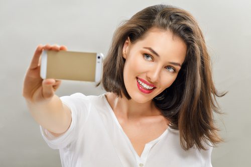 Woman holding a mobile phone taking a photo of herself